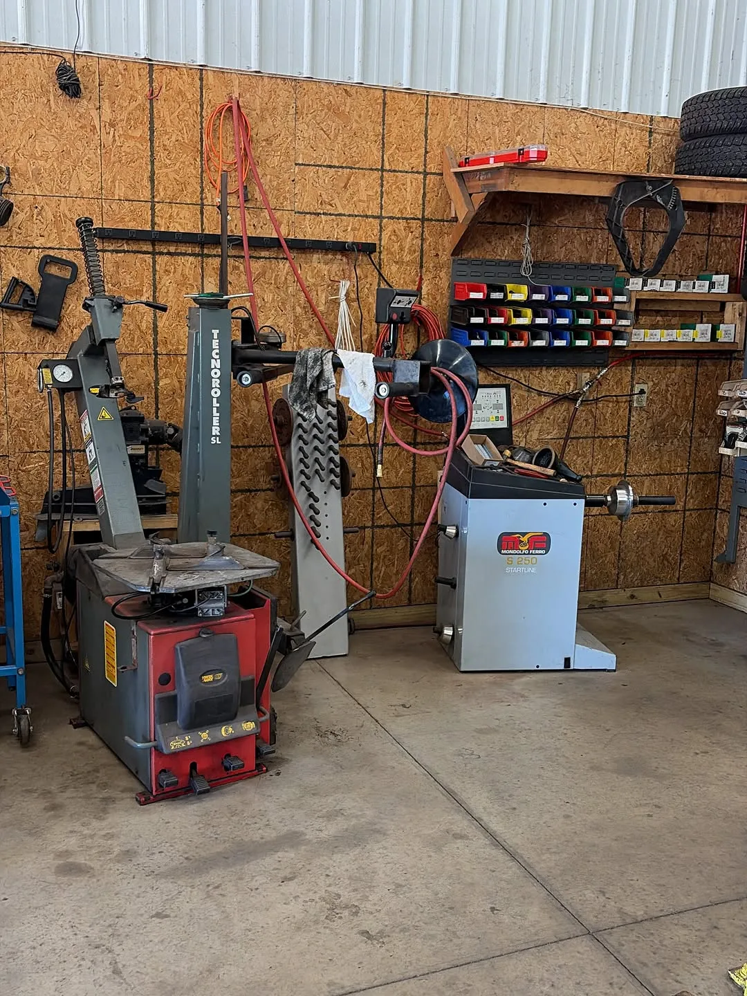 The tire changer and wheel balancer against the shop wall